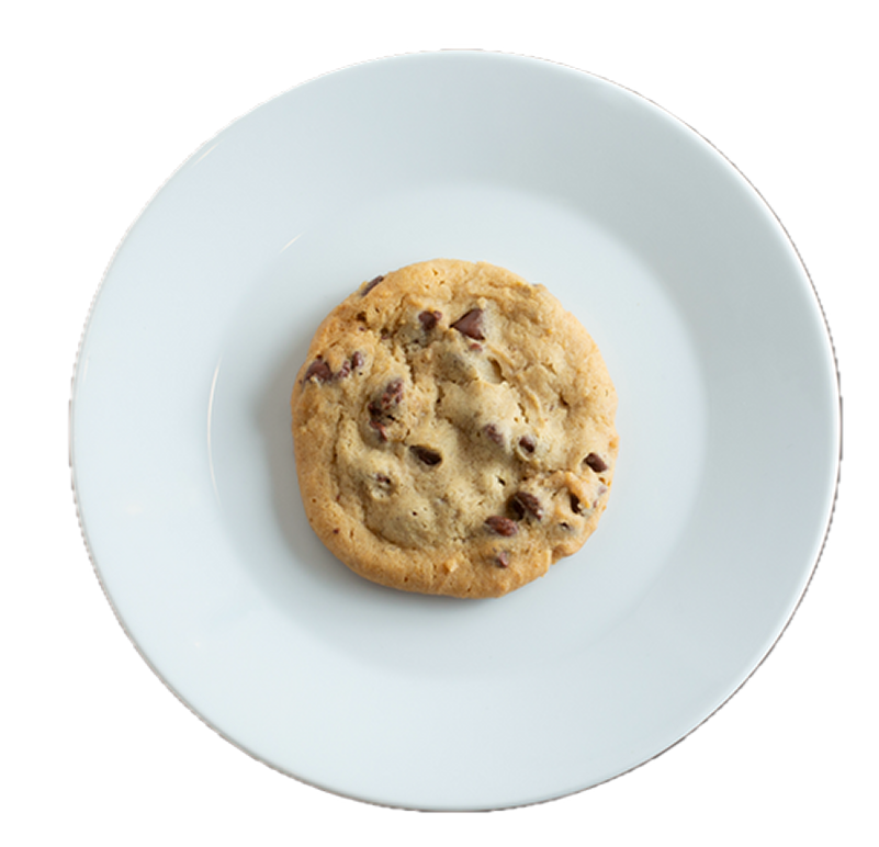 Golden chocolate chip cookie on white ceramic plate against white background