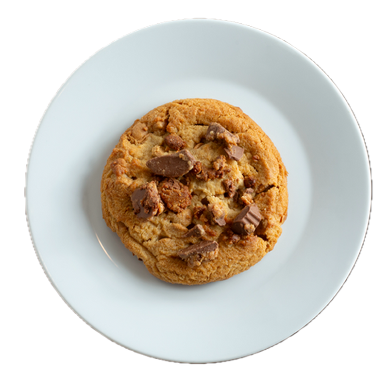 Golden chocolate chip cookie with chocolate chunks and nuts on a white ceramic plate