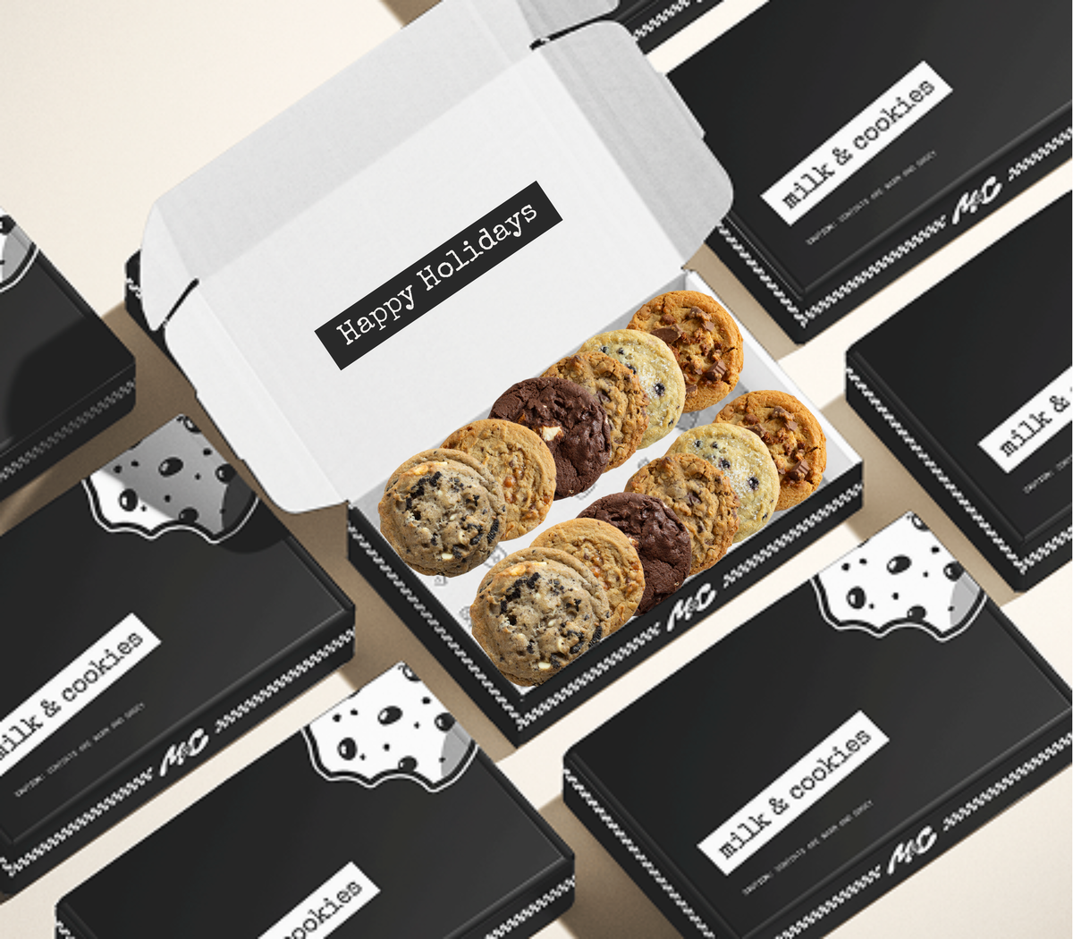 White gift box with "Happy Holidays" label containing assorted cookies, surrounded by black "milk & cookies" branded boxes