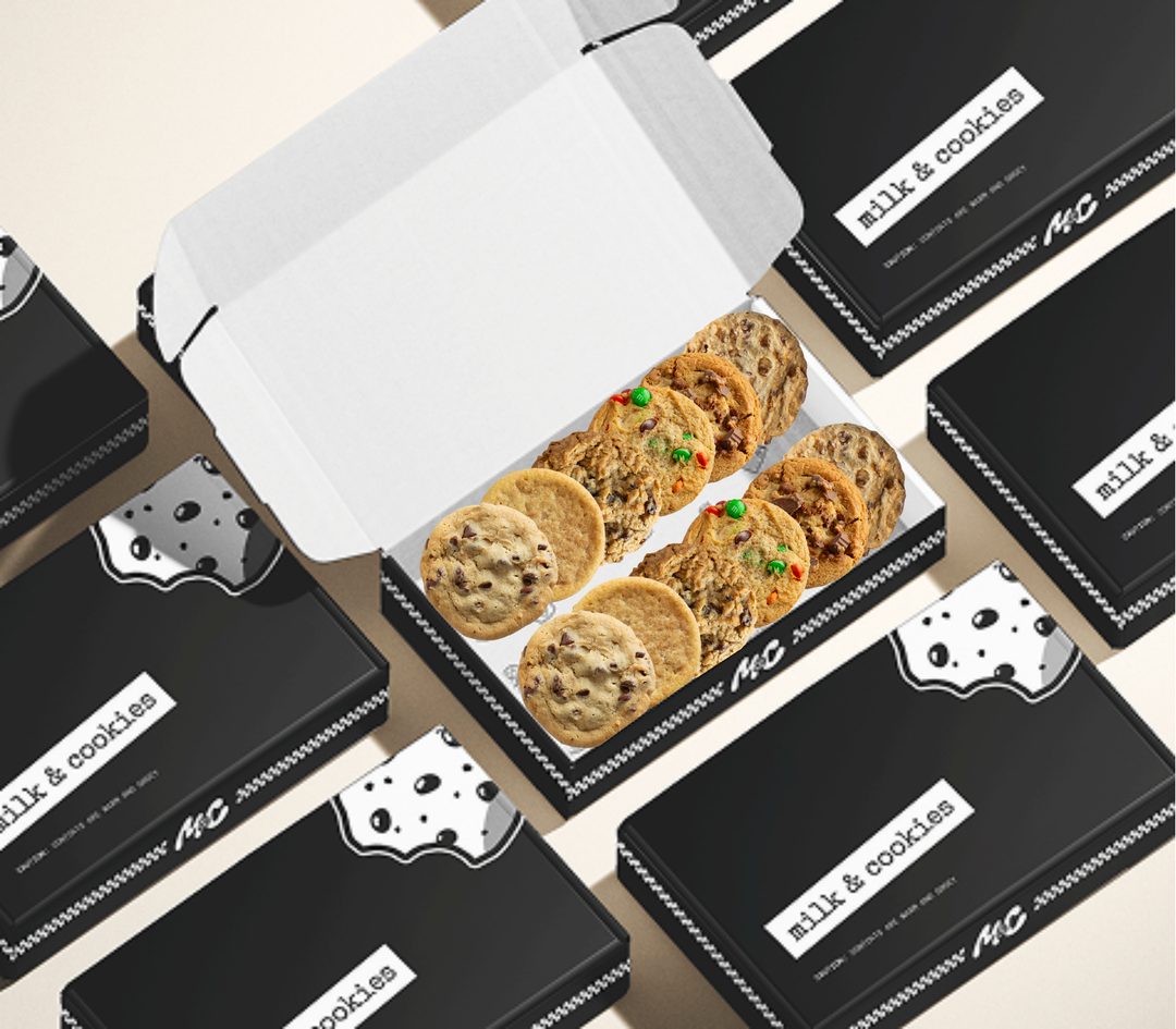 Box of assorted cookies with chocolate chips and colorful candies surrounded by black branded packaging boxes